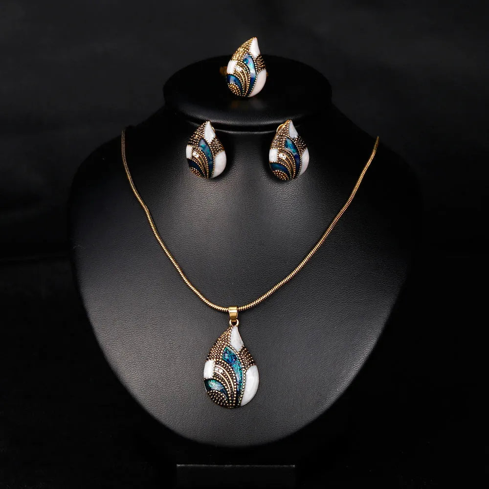 Gold water drop jewellery set with necklace, earrings, and ring on white background