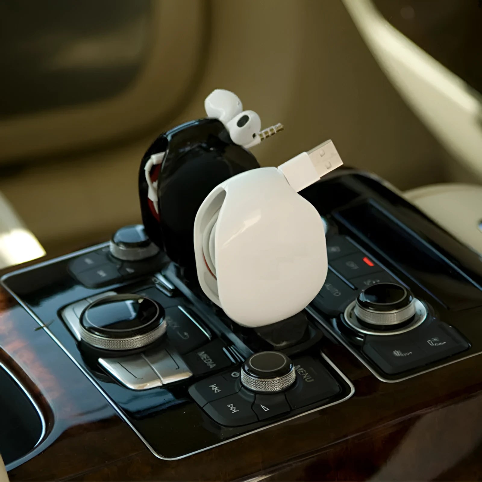 Compact automatic earphone winder in multiple colours on a grey background, showing extended cable.