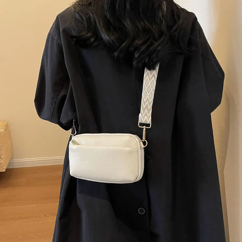 Women's cross-body bag in black, urban simplicity style, with visible sewing thread and sandwich pocket on front.