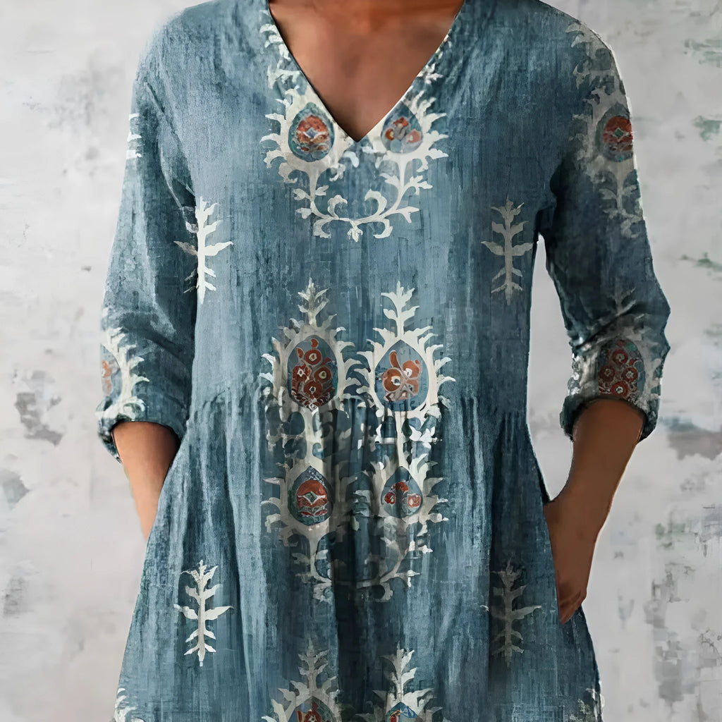 A woman wearing a loose-fitting dress with a blue and white wave print, featuring a wide waist and 3/4 length sleeves.