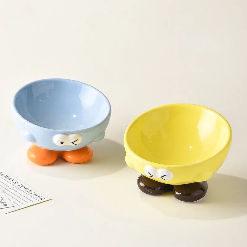 Ceramic slanted pet bowl with cute expression design in blue, yellow, and set colours for cervical spine support.