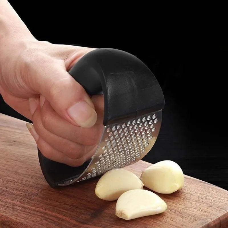Stainless steel garlic press with coloured ergonomic handle on a kitchen counter.