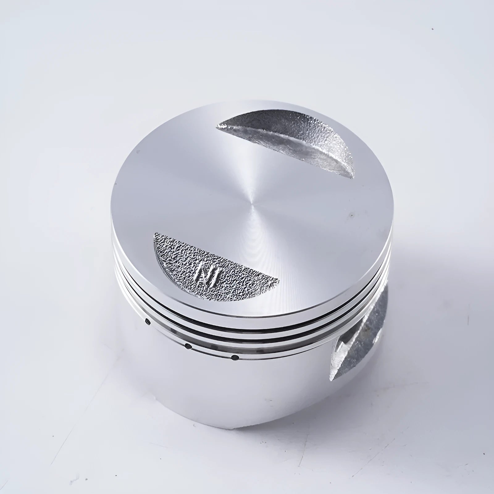 Motorcycle engine piston kit showing aluminium piston, rings, and pin for 57.4mm cylinder diameter