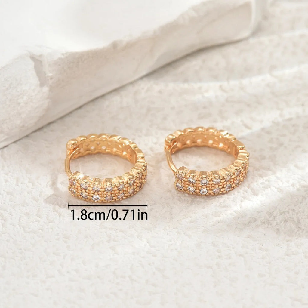 Polished copper geometry pattern ear studs with round base, central dot, and outer ring on a plain background.