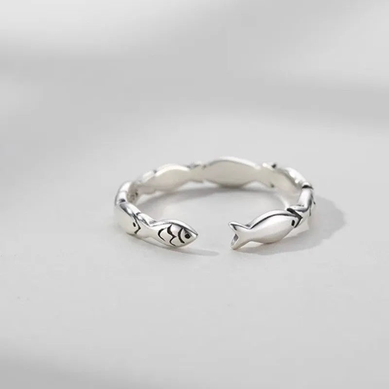 Close-up of a women's adjustable sterling silver ring with a vintage fish design on a finger.