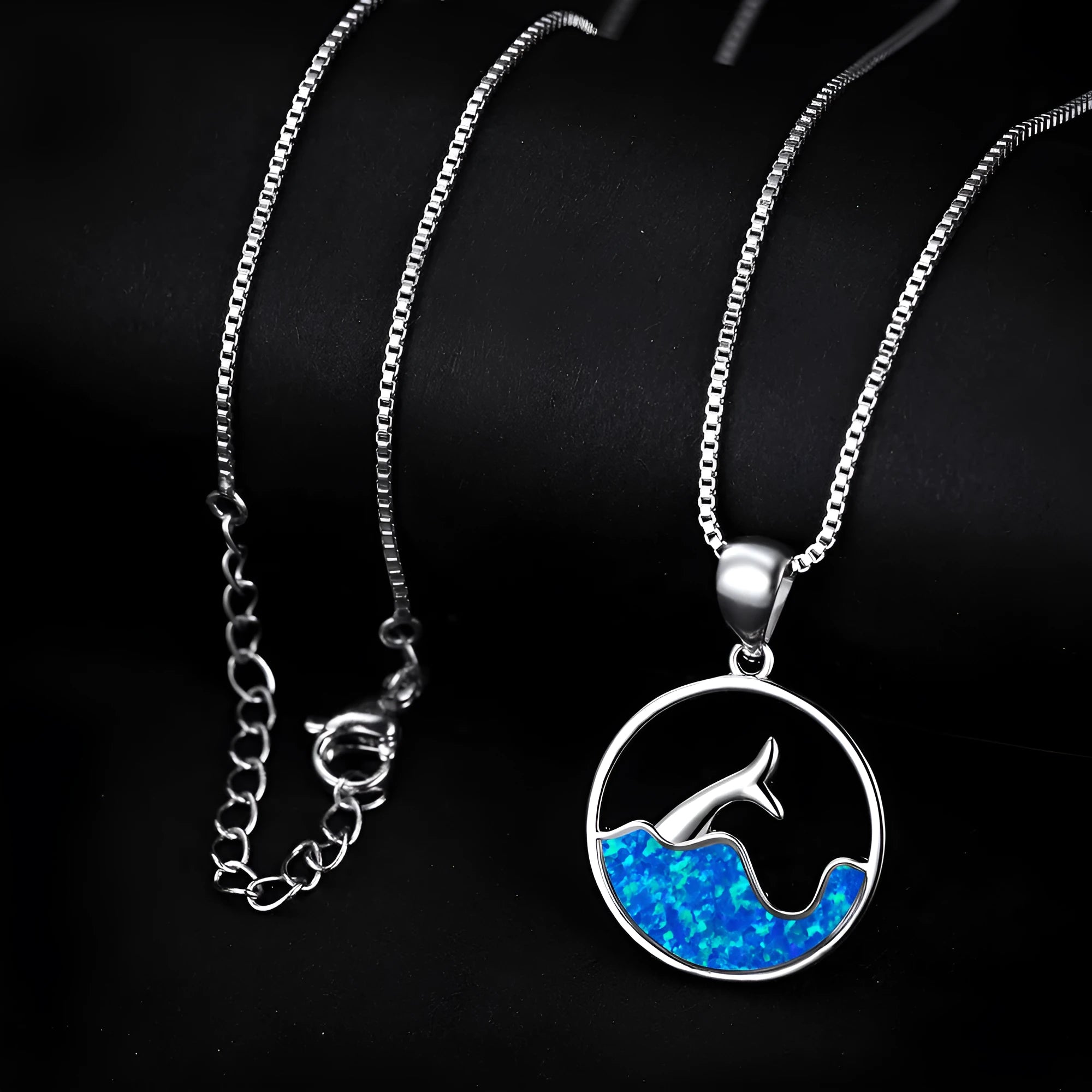 Close-up of a geometric pendant fishtail necklace with a round blue opal stone and white gold electroplated finish.