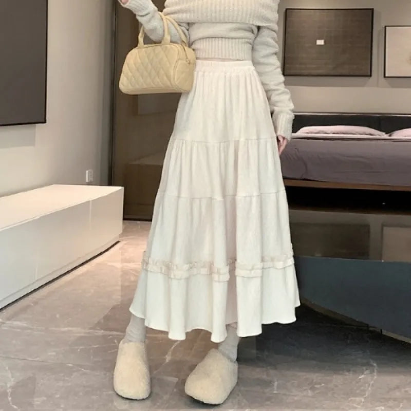 A woman wearing a beige corduroy A-line midi skirt with an elasticated waistband.