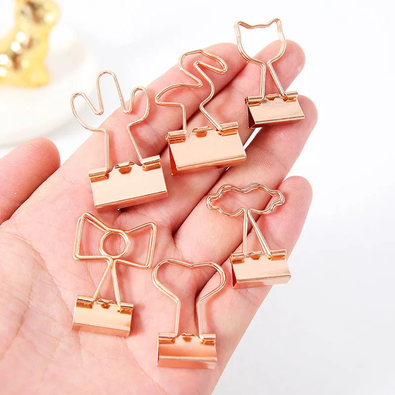 Gold metal alloy paper clip with decorative bow shape top on white background.