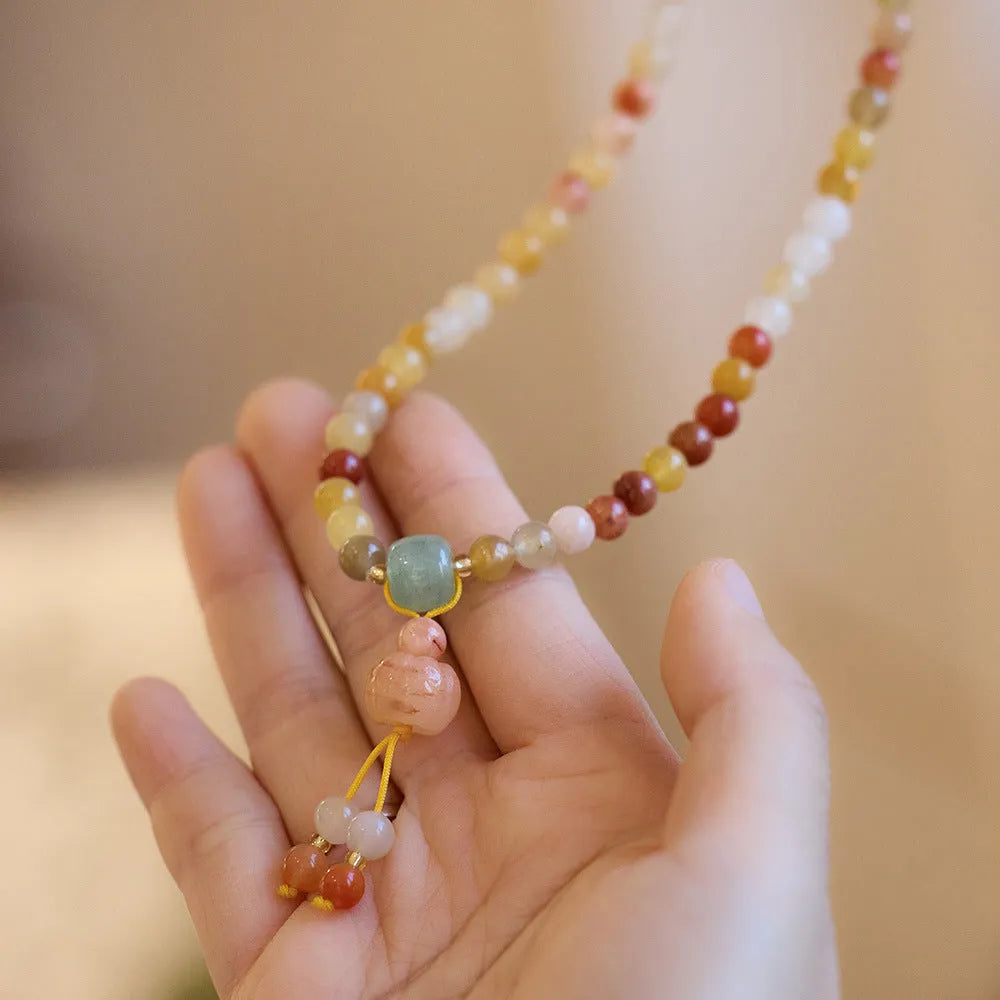 Women's handcrafted Jinsi Jade bracelet with pumpkin-shaped beads and tassels on a wrist.