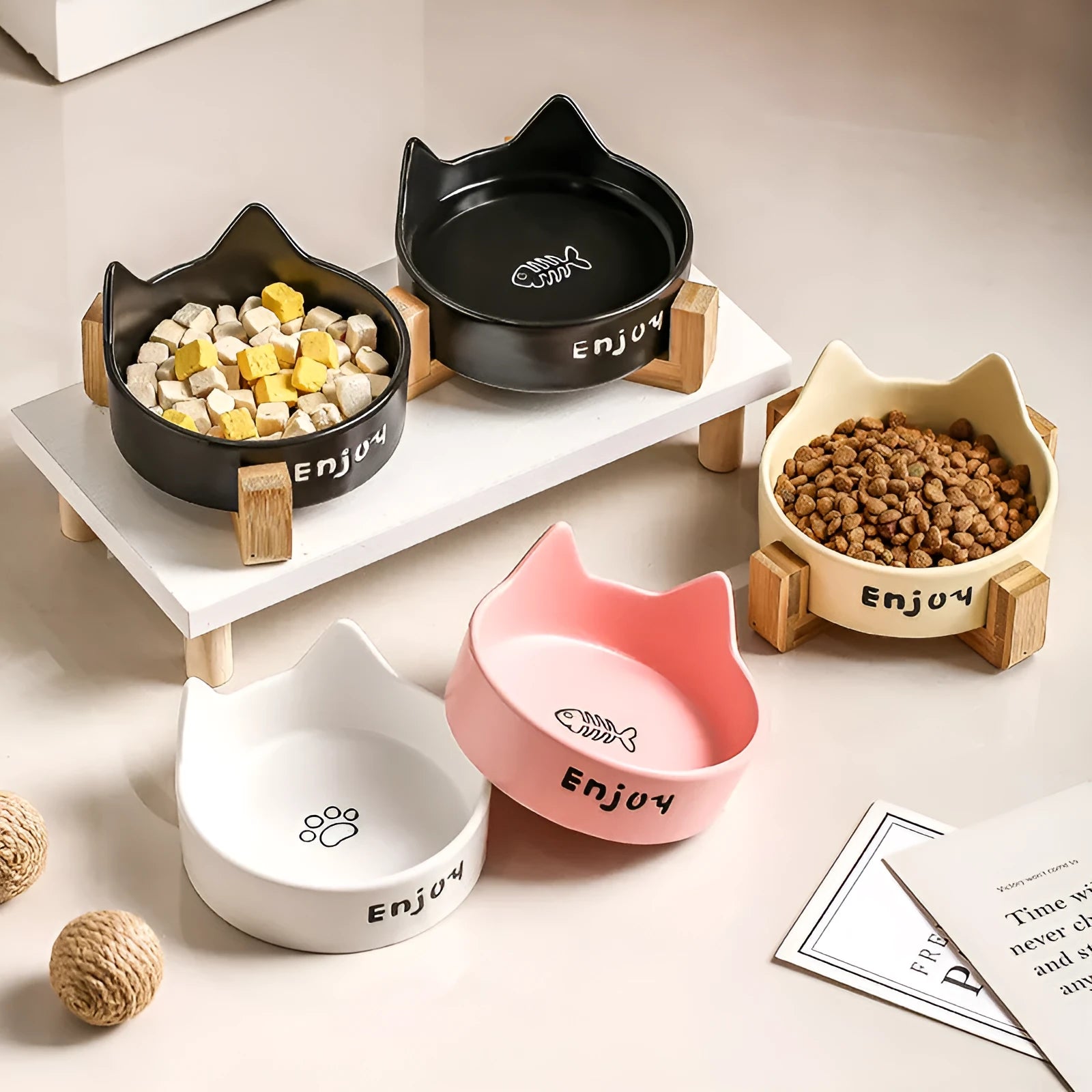 Porcelain cat bowl in a wooden anti-tip frame, showing cat's paw print design in pink.