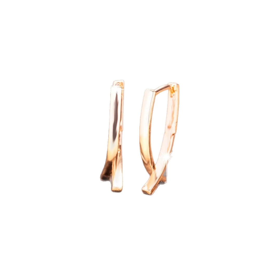 Rose gold tone cross-shaped copper earrings on a flat surface, showing polished finish and push-back clasp.