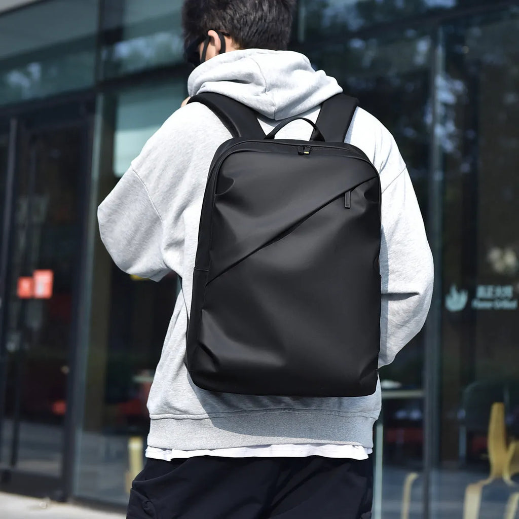 Men's large waterproof PU leather backpack in grey colour with visible stitching and laptop compartment.