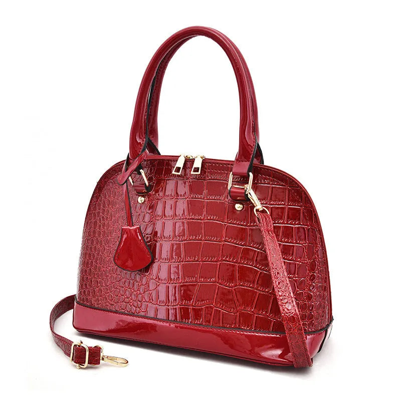 Shiny black structured shell shape crossbody shoulder bag showing large capacity and interior lining.