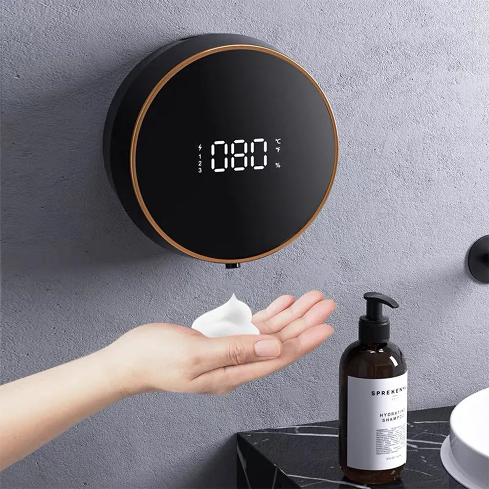 Black smart automatic foam dispenser mounted on a wall with hands activating the sensor.