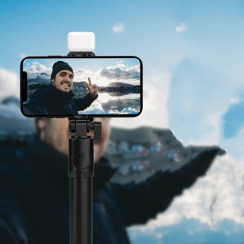 Black aluminium alloy Bluetooth selfie stick with extended tripod legs and a smartphone attached.