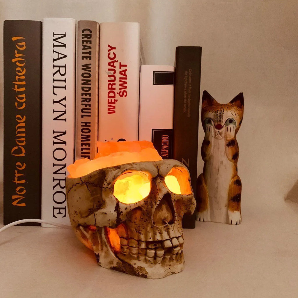 Skull-shaped Himalayan crystal salt lamp with USB dimmable LED showing warm amber light on a resin base
