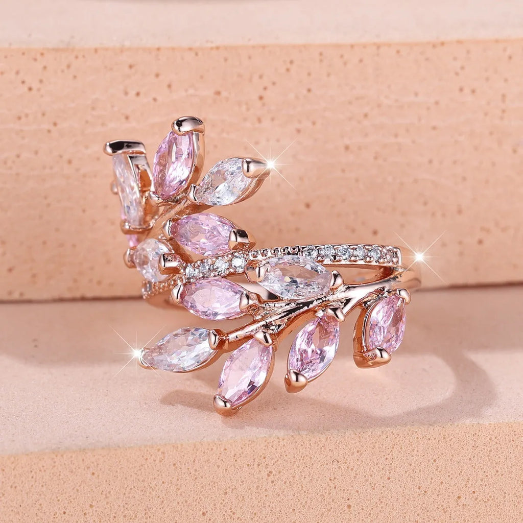 Adjustable copper leaf fashion ring with a blue zircon stone on a model's hand.
