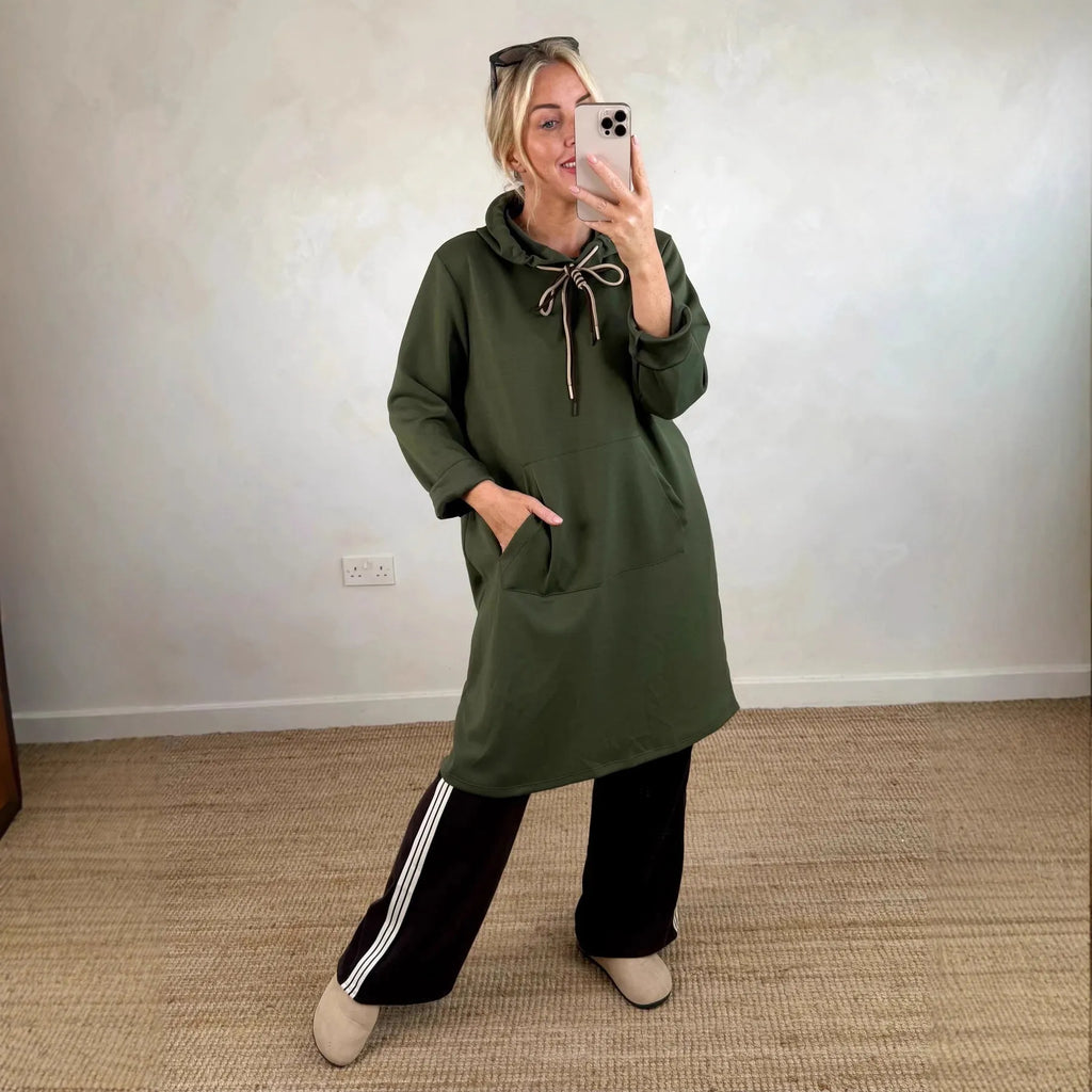 Woman wearing loose oversized knit hooded maxi dress in solid colour with front pockets, pullover style, black colour option