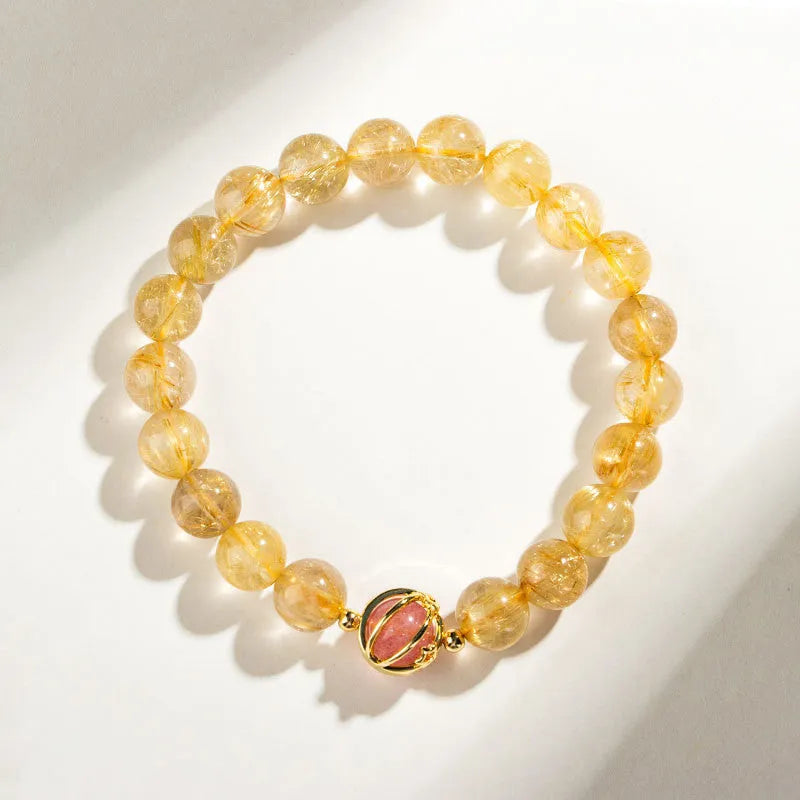 Citrine and gold rutilated quartz bracelet with diamond faceted beads on a wrist.
