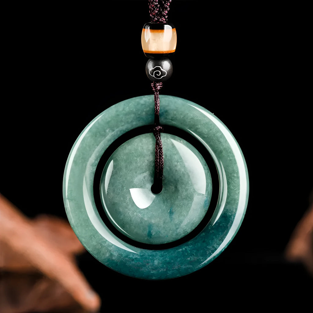 Emerald green jade pendant with carved national style design on a necklace stand