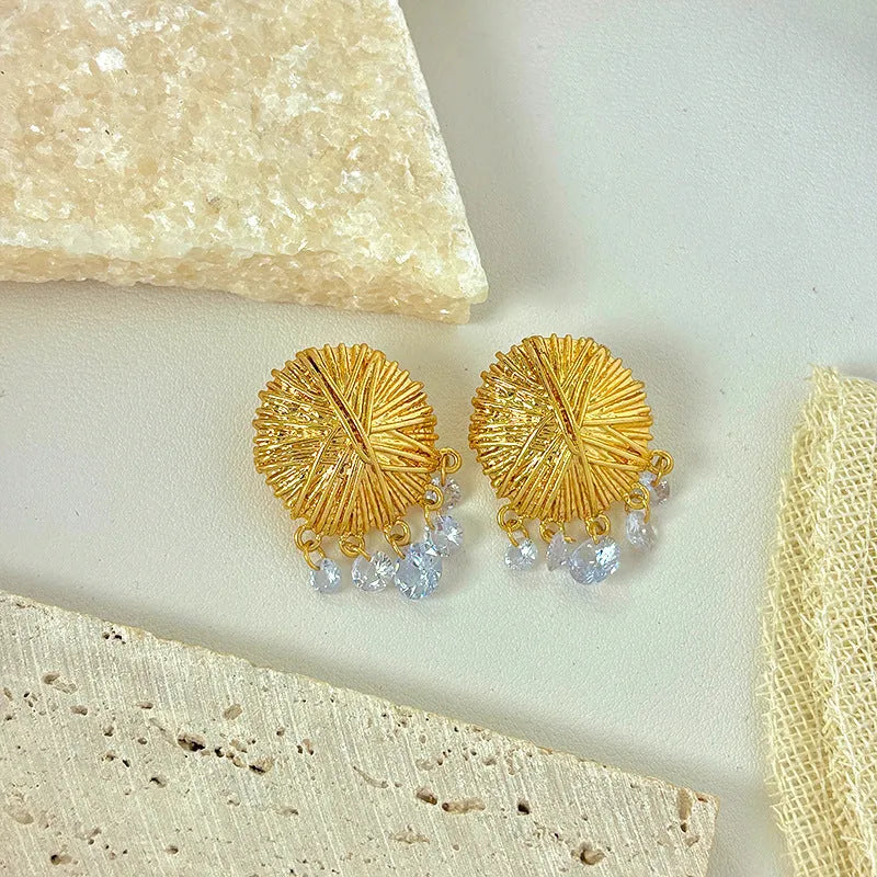A pair of circular gold geometric hoop earrings on a plain background
