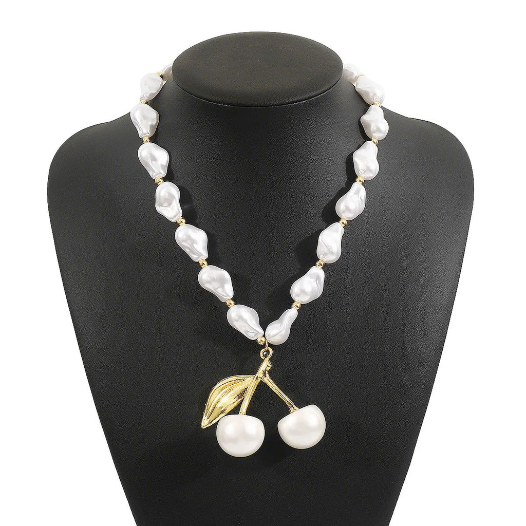 Gold-tone adjustable necklace with imitation pearls and cherry fruit pendants on a white background.