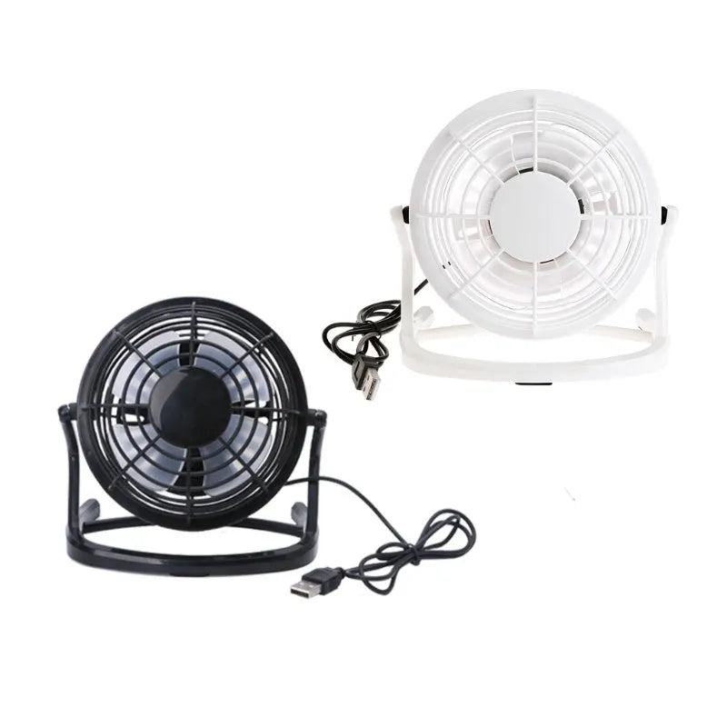 Small black and white USB desktop fan with adjustable stand on a desk next to a laptop.