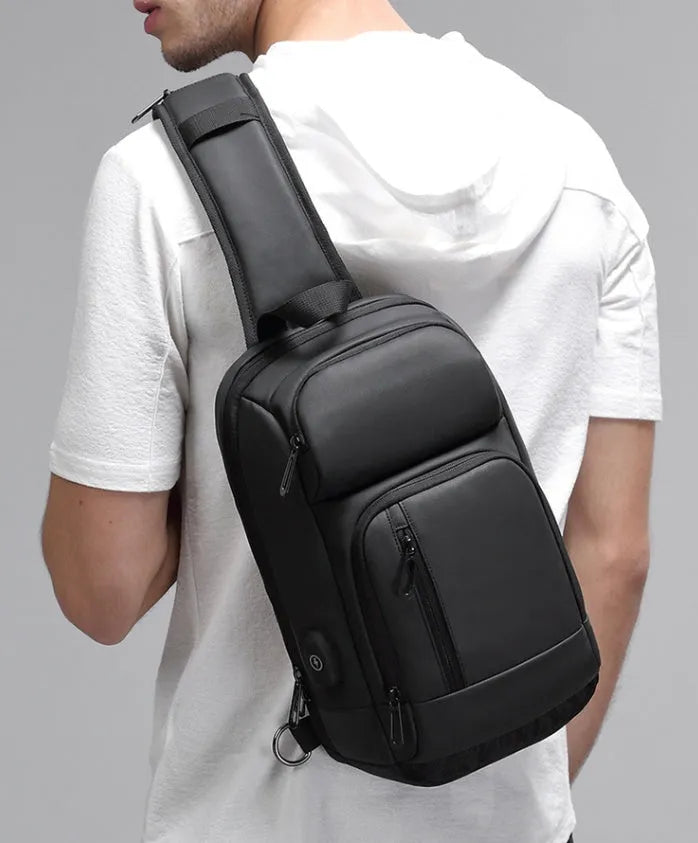 Black square PVC outdoor shoulder bag with an air cushion strap and zipper opening.
