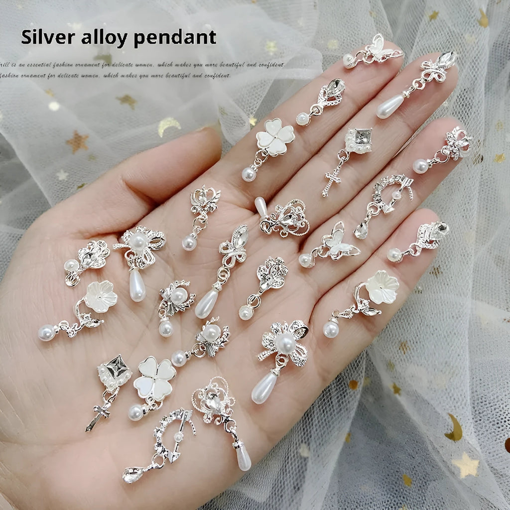 Silver nail art pendant charms with pearl and tassel details, assorted pack on black background