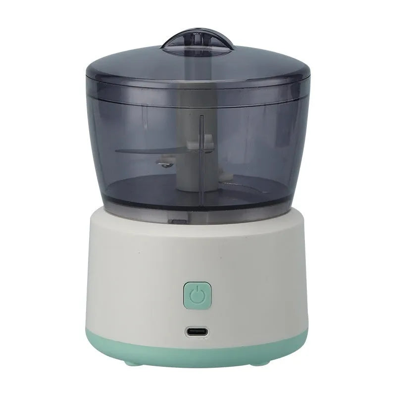 Mini electric meat grinder with transparent bowl in light green colour on a kitchen countertop.
