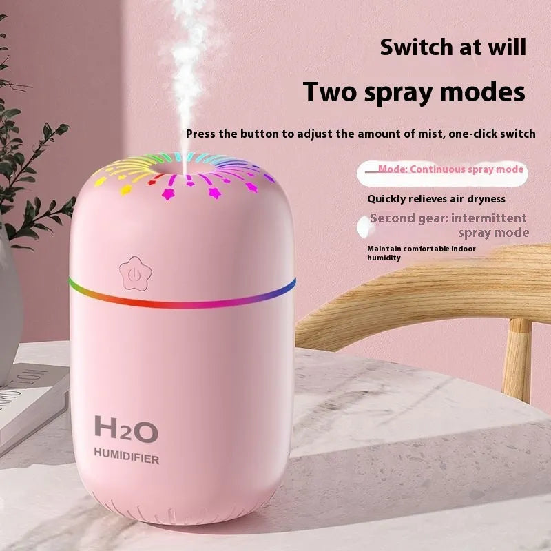 Compact white USB mini humidifier with water tank on a desk next to a laptop.