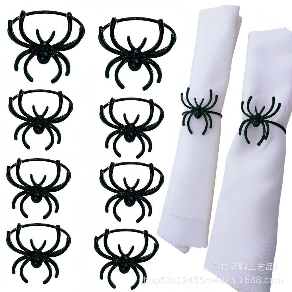 Six black alloy spider-shaped napkin rings on a dark table, showing detailed legs and a 5cm height.