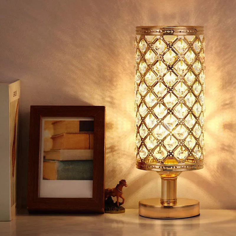 Modern crystal table lamp with gold metal base and hollow-carved crystal shade on a bedside table