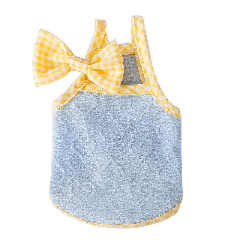 Small dog wearing a blue elastic vest with a heart texture and bow suspenders, with a matching hairband.
