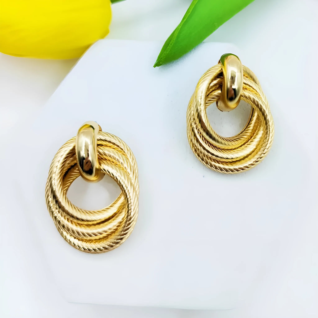 Gold metal geometric ring embossed twisted stud earrings on display