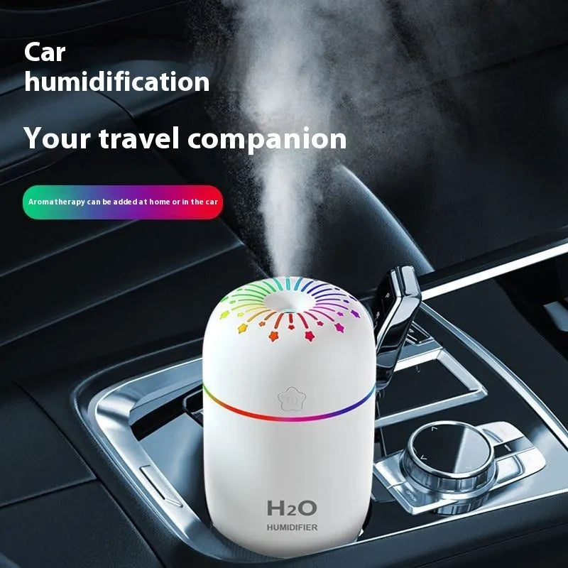 Compact white USB mini humidifier with water tank on a desk next to a laptop.