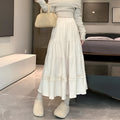 A woman wearing a beige corduroy A-line midi skirt with an elasticated waistband.