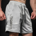 Man wearing light grey loose-fit mesh sport shorts with a straight leg cut.