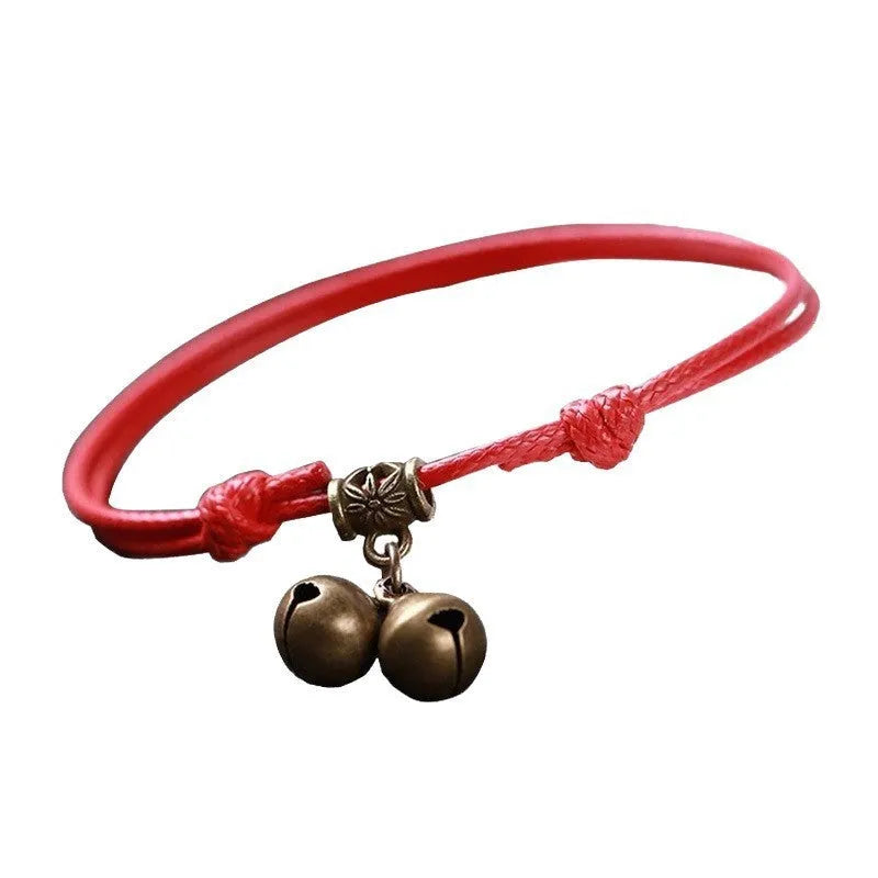Close-up of an adjustable black nylon rope dog collar featuring a shiny brass bell.