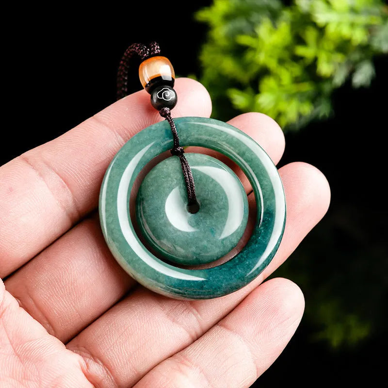 Emerald green jade pendant with carved national style design on a necklace stand