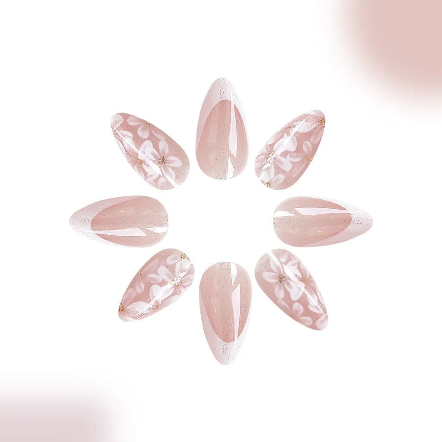 Short almond-shaped plastic false nails with glossy white French tips and pink glitter powder flower design.