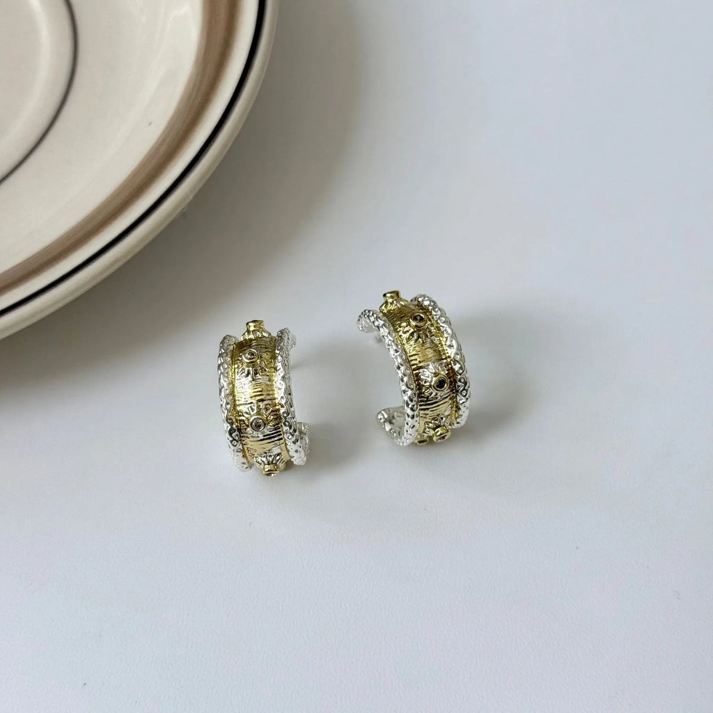 Gold and silver C-shaped brushed ring earrings on display, copper with 925 silver needles
