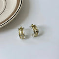 Gold and silver C-shaped brushed ring earrings on display, copper with 925 silver needles