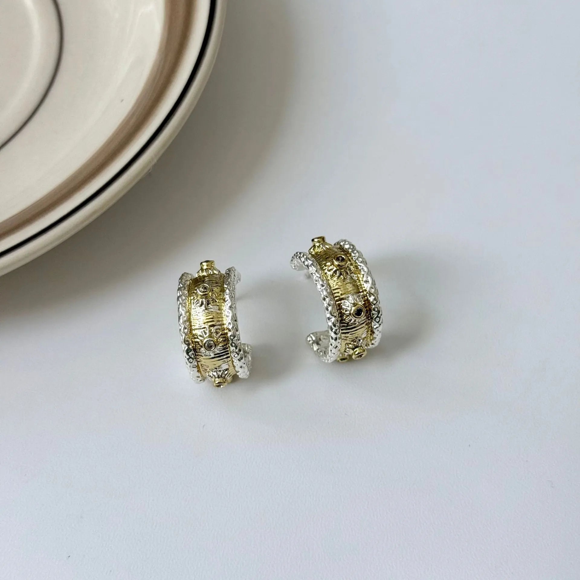 Gold and silver C-shaped brushed ring earrings on display, copper with 925 silver needles