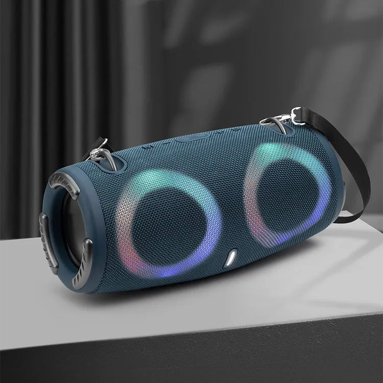 War Drum portable Bluetooth speaker with glowing RGB light ring in camouflage colour, sitting on grass.