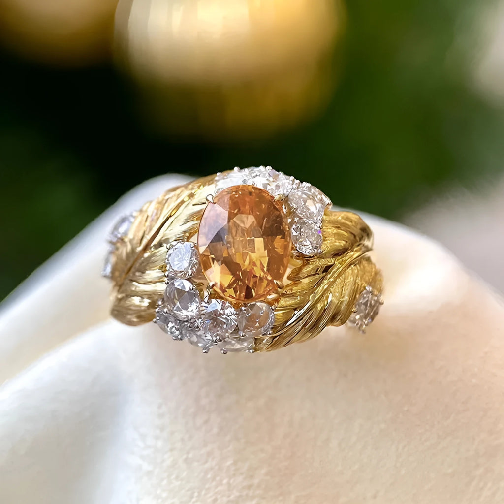 Gold-coloured embossed feather ring with geometric pattern and yellow zircon stones on a white background.