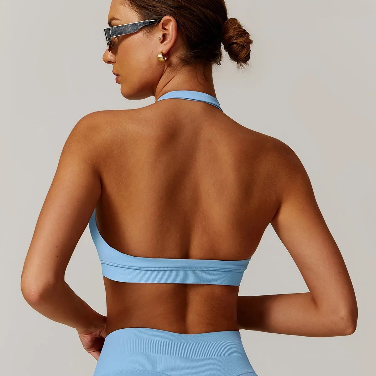 Women's halter neck yoga sports bra in plum purple, shown from the front, showcasing the tie detail and medium support fit.