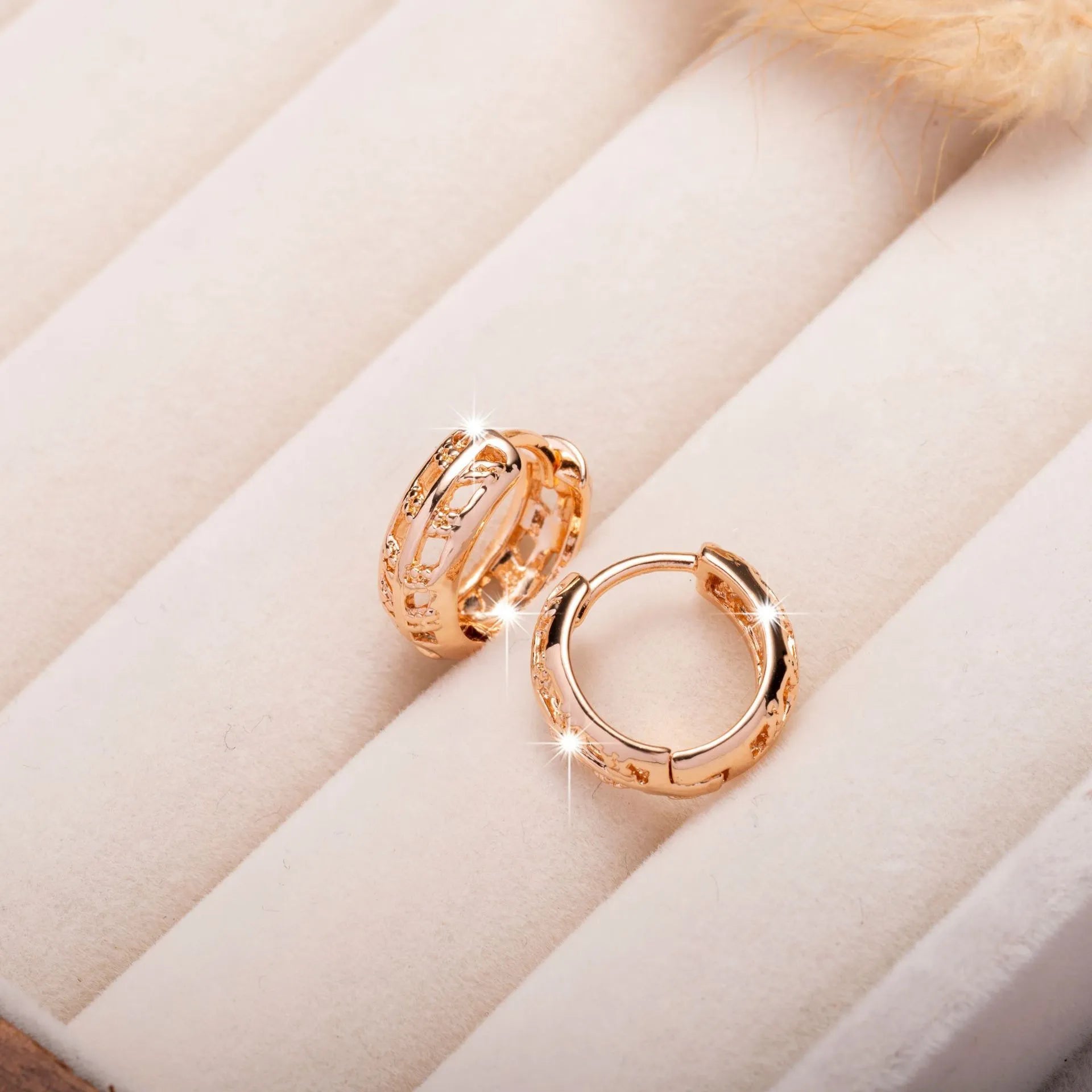 Close-up of rose gold plated copper stud earrings with hollow leaf and heart shapes on a grey background.