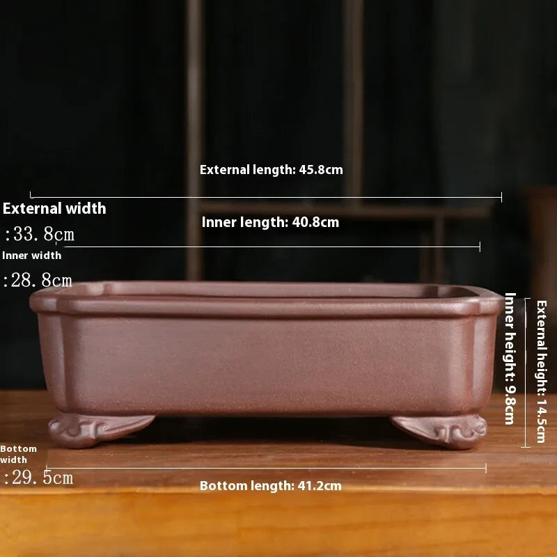 Rectangular antique purple sand bonsai pot with cut corners on a floor.