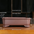 Rectangular antique purple sand bonsai pot with cut corners on a floor.